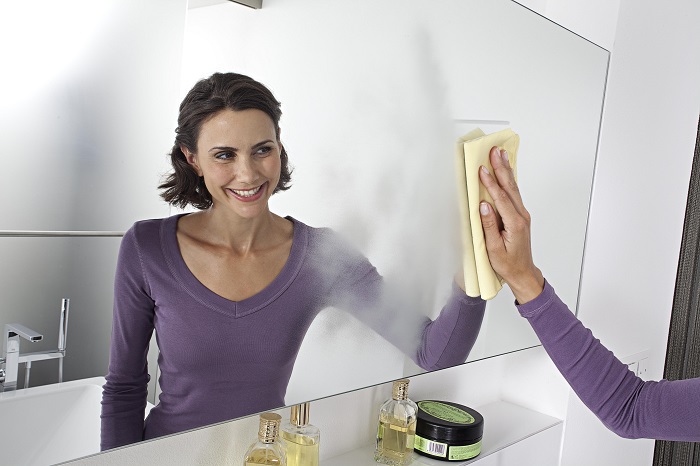 Женщина вытирает зеркало